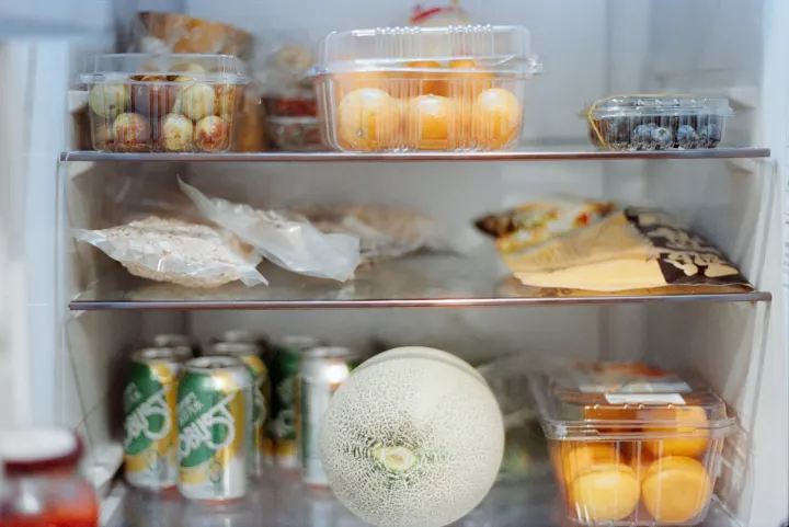 Various foods and drinks stocked inside an open refrigerator