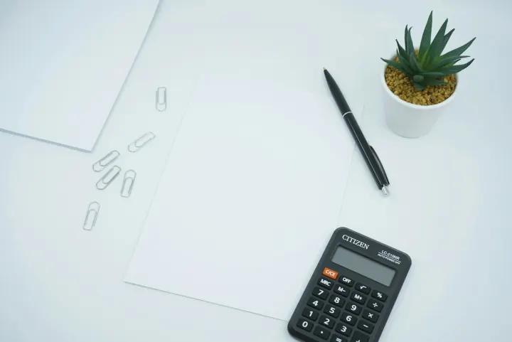 Black calculator beside black pen on white printer paper