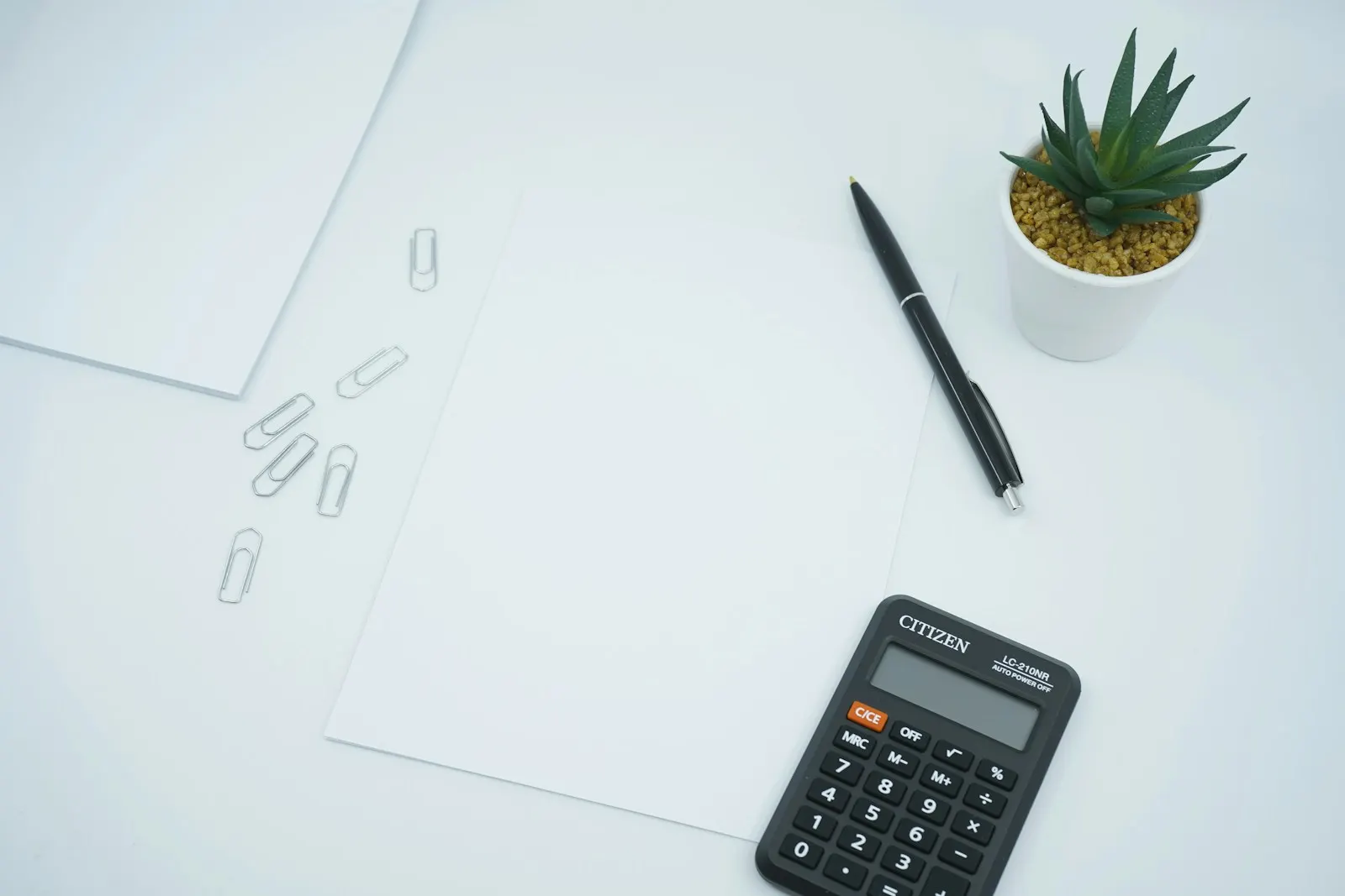 Black calculator beside black pen on white printer paper