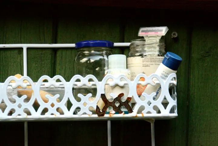 White metal caddy with toiletries on a green wooden wall