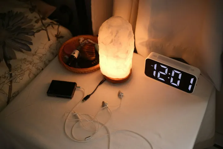 Nightstand with a lamp, clock, and chargers